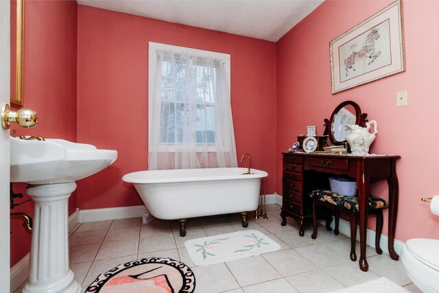 bathroom with a tub to relax in, tile patterned floors, and toilet