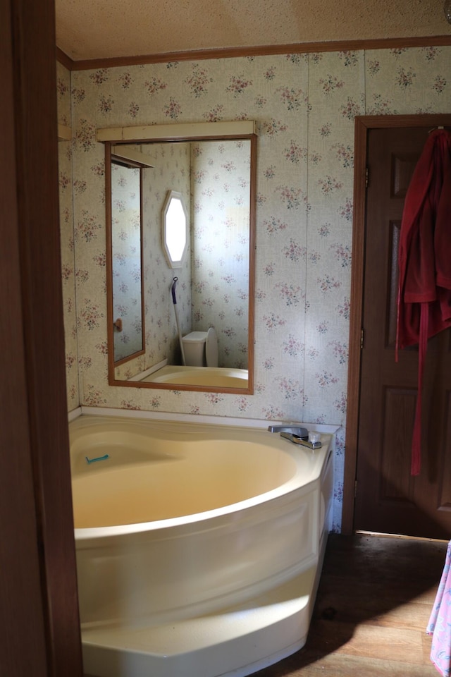 bathroom with a textured ceiling, hardwood / wood-style flooring, and a bathtub