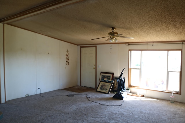 unfurnished room featuring a textured ceiling, carpet, ornamental molding, and ceiling fan