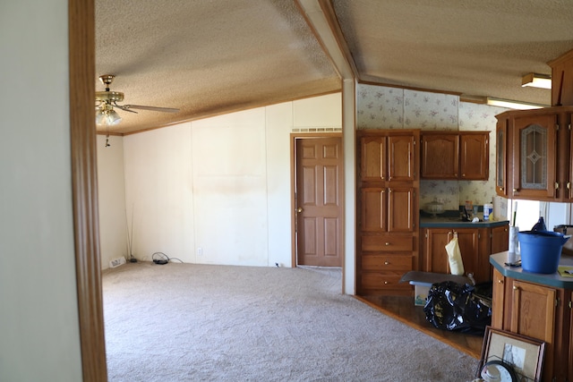 kitchen featuring vaulted ceiling, a textured ceiling, carpet floors, and ceiling fan