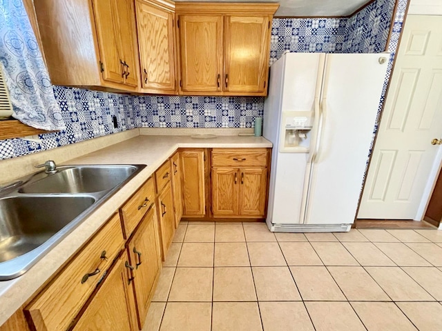 kitchen featuring white refrigerator with ice dispenser, light tile patterned flooring, backsplash, and sink