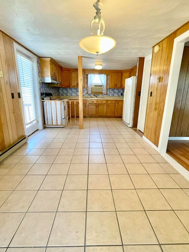 kitchen with wood walls, light tile patterned floors, tasteful backsplash, white appliances, and decorative light fixtures