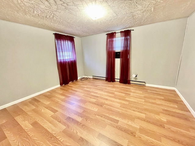 spare room with a baseboard radiator, a textured ceiling, and hardwood / wood-style floors