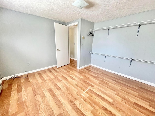 unfurnished bedroom featuring a textured ceiling, a closet, and light hardwood / wood-style floors