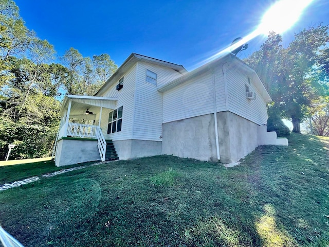 view of side of property featuring a lawn, a porch, and ceiling fan