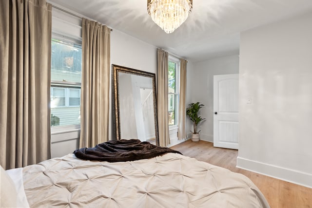 bedroom with light hardwood / wood-style flooring and a chandelier