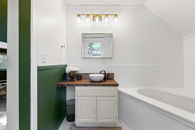 bathroom featuring tile patterned floors, vanity, a tub to relax in, and vaulted ceiling