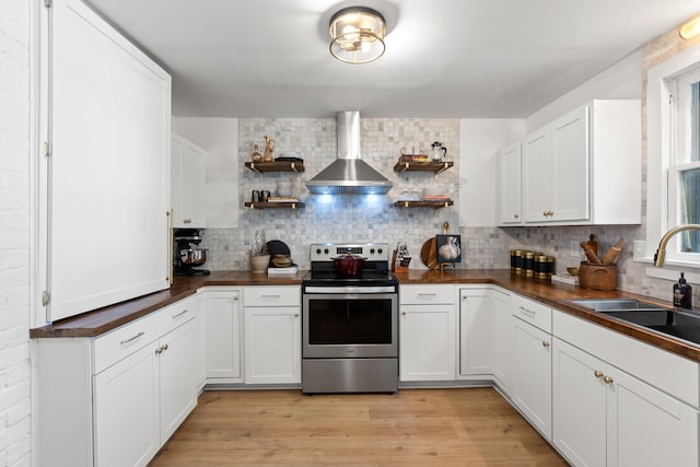 kitchen with stainless steel range with electric stovetop, white cabinets, wall chimney range hood, and sink