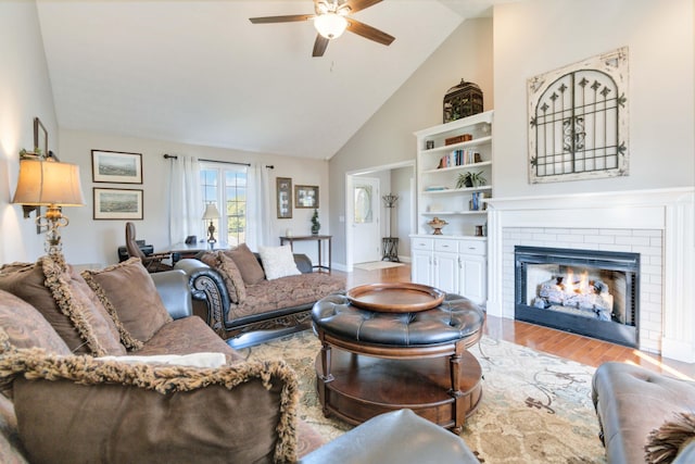 living room with light hardwood / wood-style floors, a fireplace, ceiling fan, and high vaulted ceiling