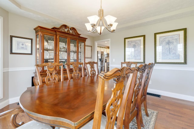 dining room with hardwood / wood-style flooring and a chandelier