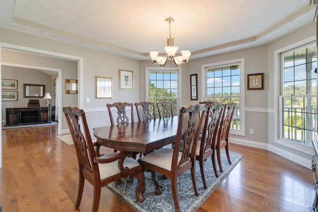 dining room featuring an inviting chandelier, wood-type flooring, a textured ceiling, and a healthy amount of sunlight