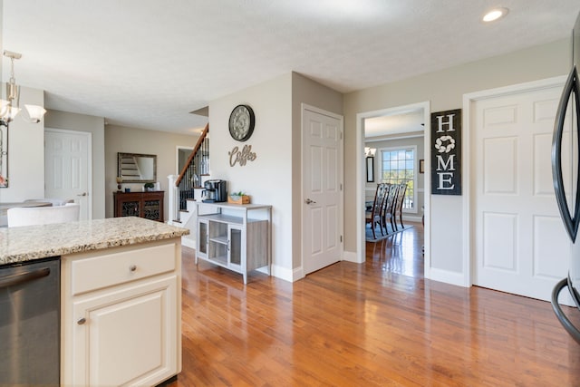 kitchen featuring light stone countertops, pendant lighting, a textured ceiling, wood-type flooring, and a notable chandelier