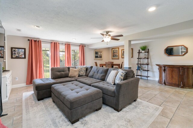 living room with ceiling fan, a textured ceiling, and light tile patterned floors