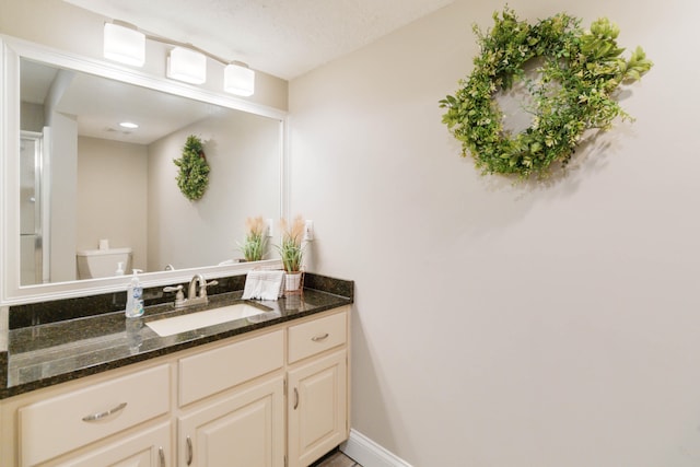 bathroom featuring a textured ceiling, vanity, and toilet