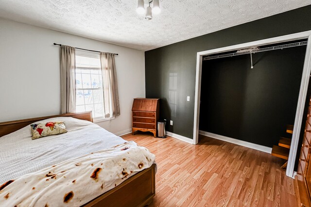 bedroom with a textured ceiling, a closet, and light hardwood / wood-style flooring