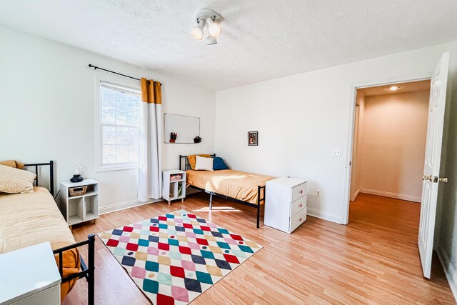 bedroom with a textured ceiling and light wood-type flooring