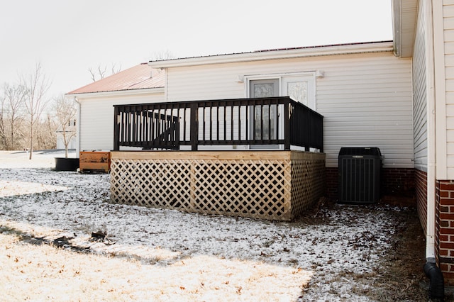 snow covered back of property featuring cooling unit and a deck