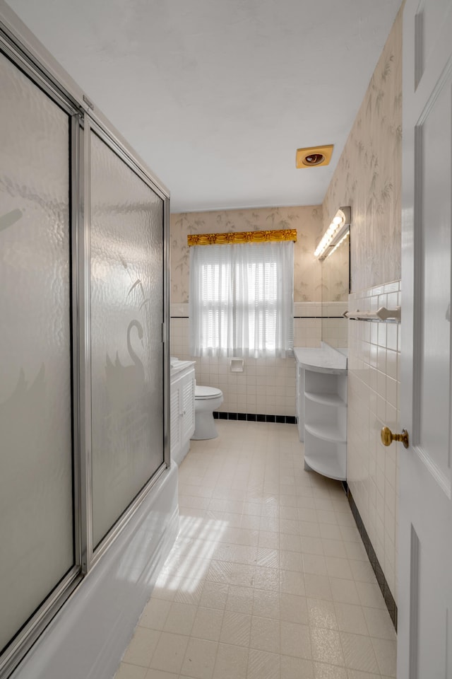 full bathroom with tile walls, combined bath / shower with glass door, vanity, and toilet