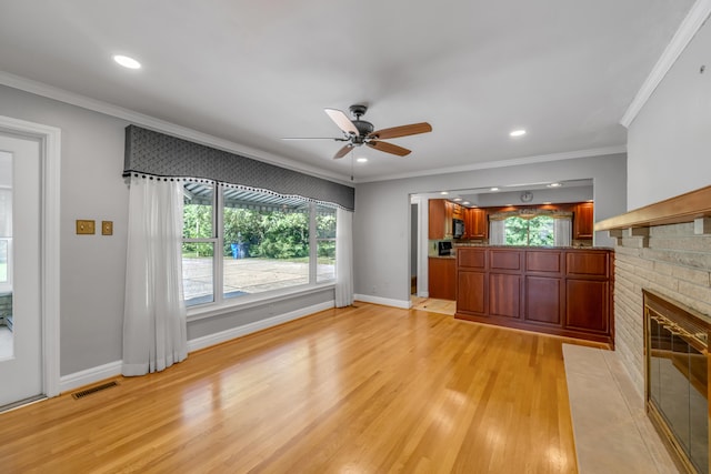 unfurnished living room featuring a brick fireplace, light hardwood / wood-style floors, ceiling fan, and crown molding