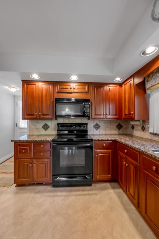 kitchen with light stone counters, kitchen peninsula, tasteful backsplash, light hardwood / wood-style flooring, and black appliances