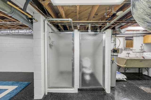 bathroom featuring washer / dryer, a shower with shower door, and sink