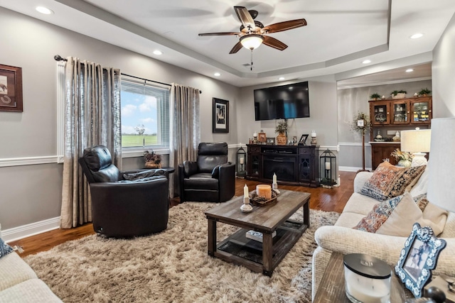 living room featuring ceiling fan, hardwood / wood-style flooring, and a raised ceiling