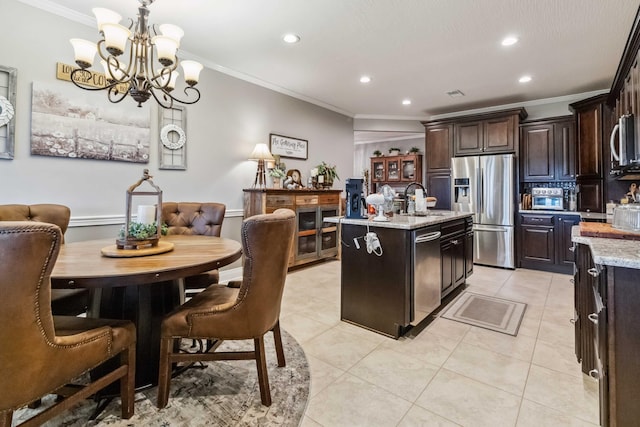 kitchen featuring an island with sink, decorative light fixtures, appliances with stainless steel finishes, light stone countertops, and crown molding