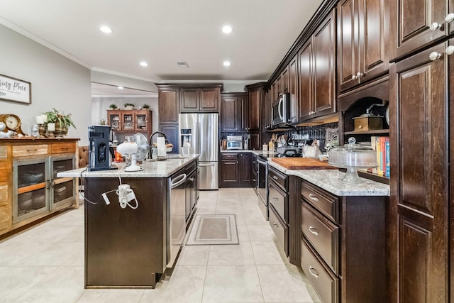 kitchen with a kitchen island with sink, sink, appliances with stainless steel finishes, dark brown cabinetry, and ornamental molding