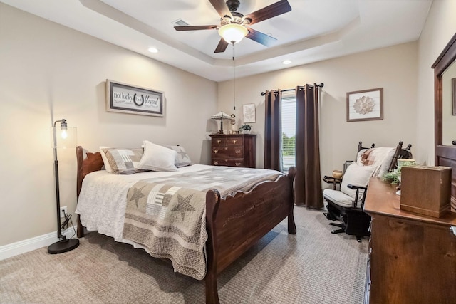 carpeted bedroom with a raised ceiling and ceiling fan