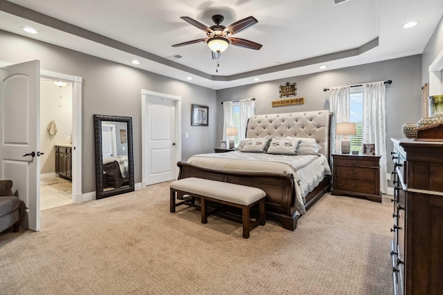 bedroom with multiple windows, a tray ceiling, ceiling fan, and light colored carpet