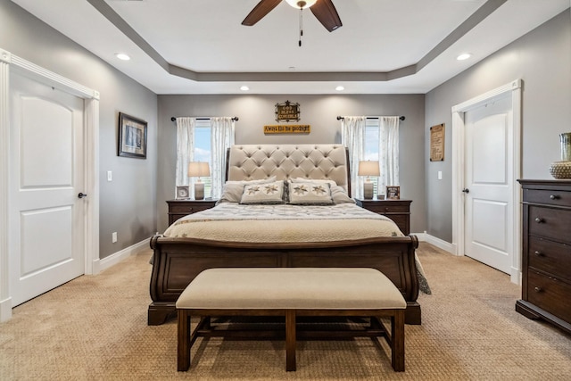 carpeted bedroom with ceiling fan and a raised ceiling