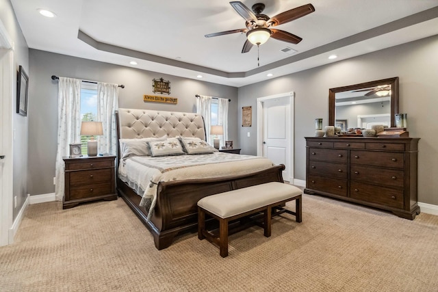 bedroom featuring a raised ceiling, ceiling fan, and light colored carpet