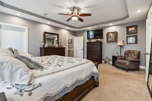 bedroom with light carpet, ceiling fan, and a raised ceiling