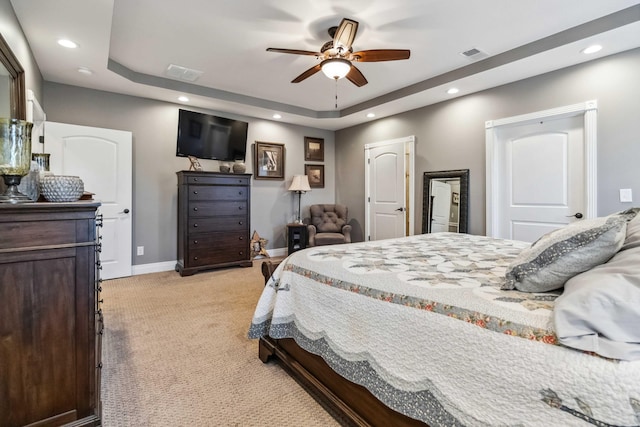 carpeted bedroom with ceiling fan and a raised ceiling