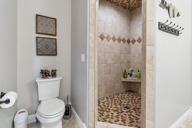 bathroom with tile patterned floors, toilet, and tiled shower