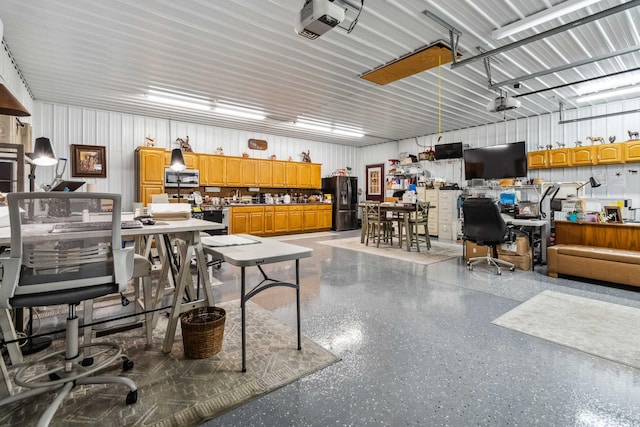 garage featuring black fridge, a garage door opener, and a workshop area