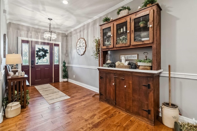 foyer featuring an inviting chandelier, crown molding, and light hardwood / wood-style floors