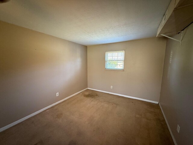 spare room featuring baseboards, a textured ceiling, and carpet flooring