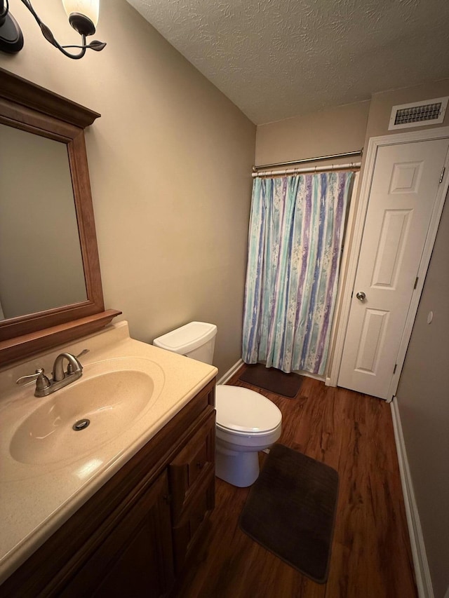 full bath with visible vents, toilet, a shower with curtain, wood finished floors, and vanity