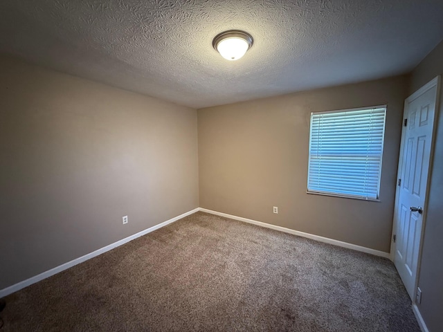 carpeted empty room with a textured ceiling and baseboards