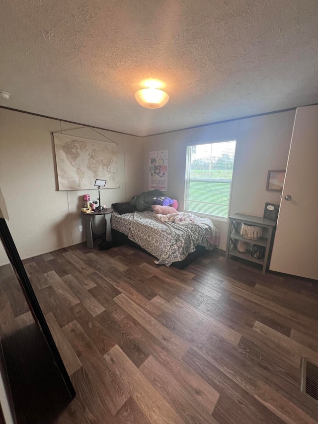 bedroom with dark wood-type flooring and a textured ceiling