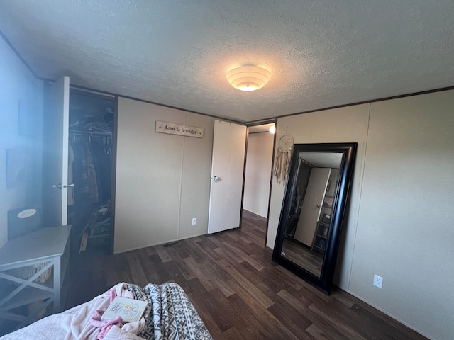 bedroom with a textured ceiling and dark hardwood / wood-style floors