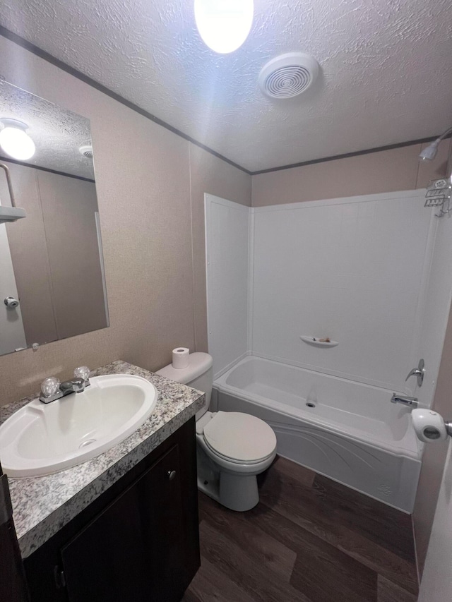 full bathroom with a textured ceiling, hardwood / wood-style floors, toilet, vanity, and tub / shower combination