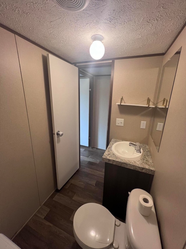 bathroom with vanity, toilet, wood-type flooring, and a textured ceiling