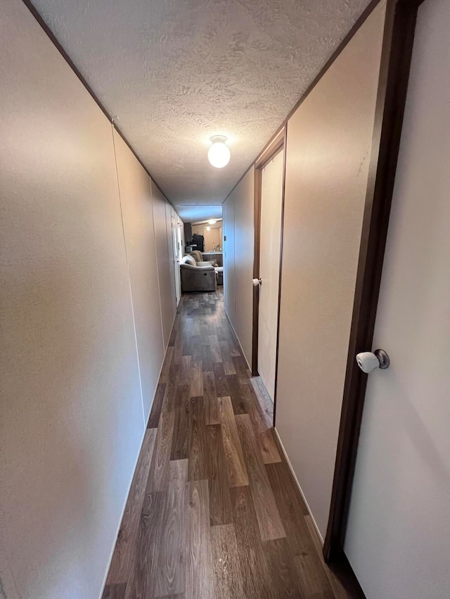 corridor featuring a textured ceiling and dark wood-type flooring