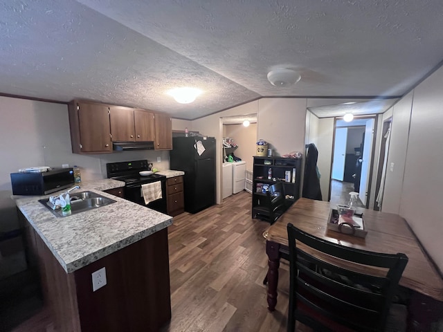 kitchen featuring wood-type flooring, separate washer and dryer, vaulted ceiling, black appliances, and sink