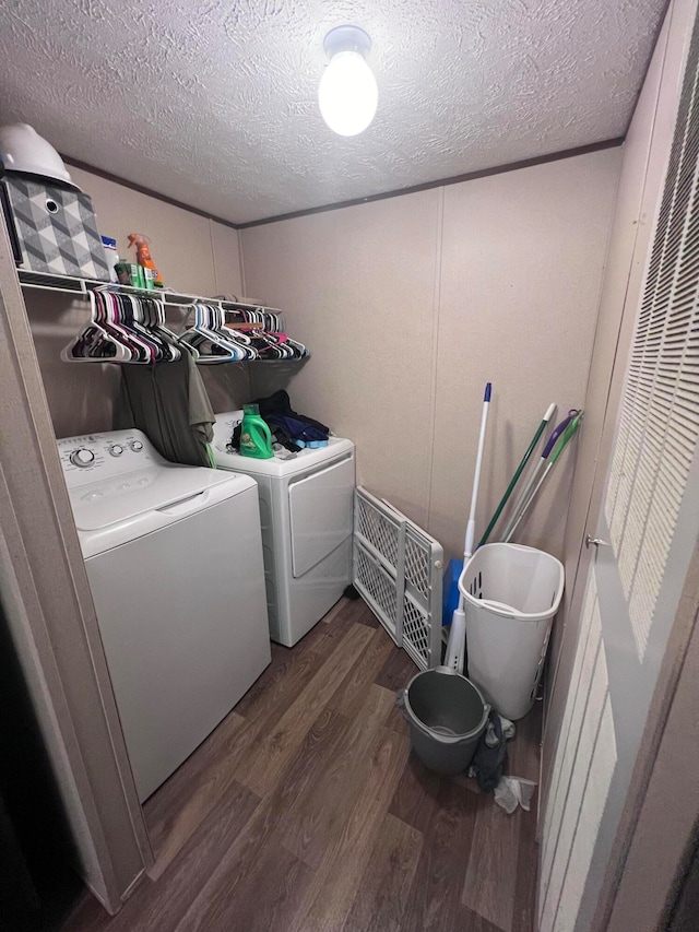 laundry area with a textured ceiling, washer and clothes dryer, and dark hardwood / wood-style flooring