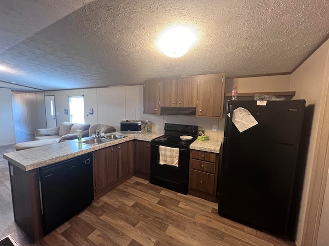 kitchen with kitchen peninsula, dark hardwood / wood-style flooring, a textured ceiling, black appliances, and sink