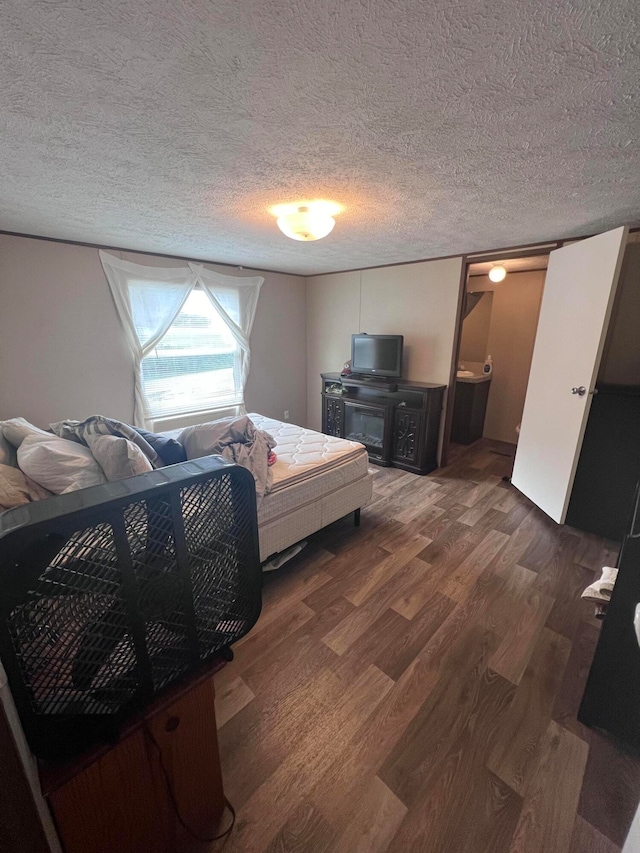 bedroom featuring a textured ceiling, ensuite bathroom, and dark hardwood / wood-style flooring