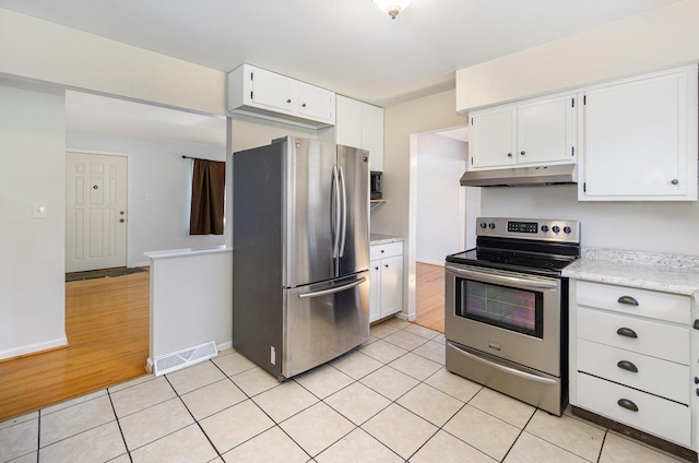 kitchen with light tile patterned floors, under cabinet range hood, stainless steel appliances, visible vents, and white cabinetry